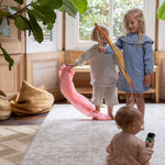 Three children playing with colorful ribbons on a designer baby play mat that matches home decor