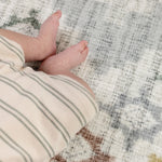 Close-up of a baby's hand and foot on a protective floor covering mat