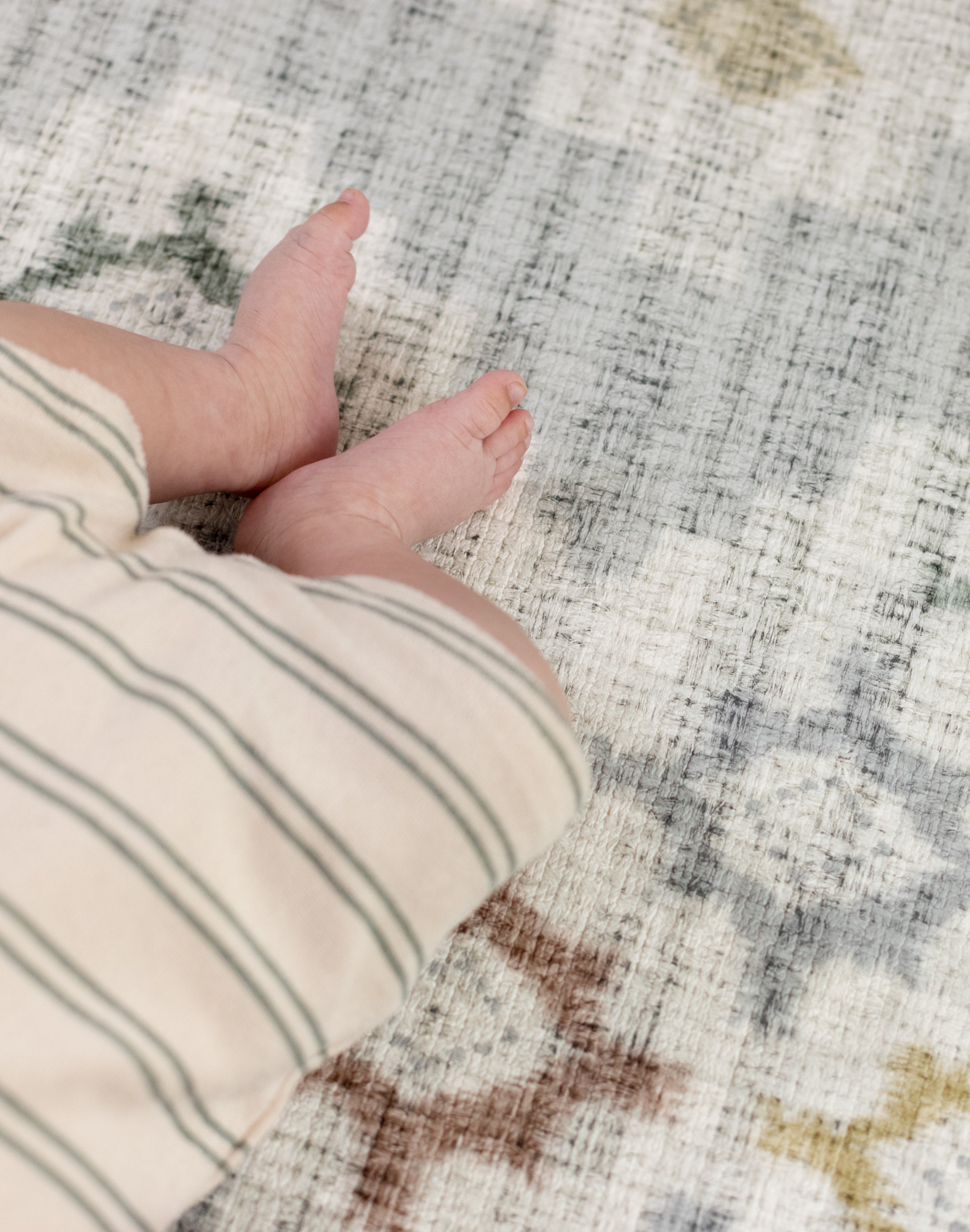 Close-up of a baby's hand and foot on a protective floor covering mat