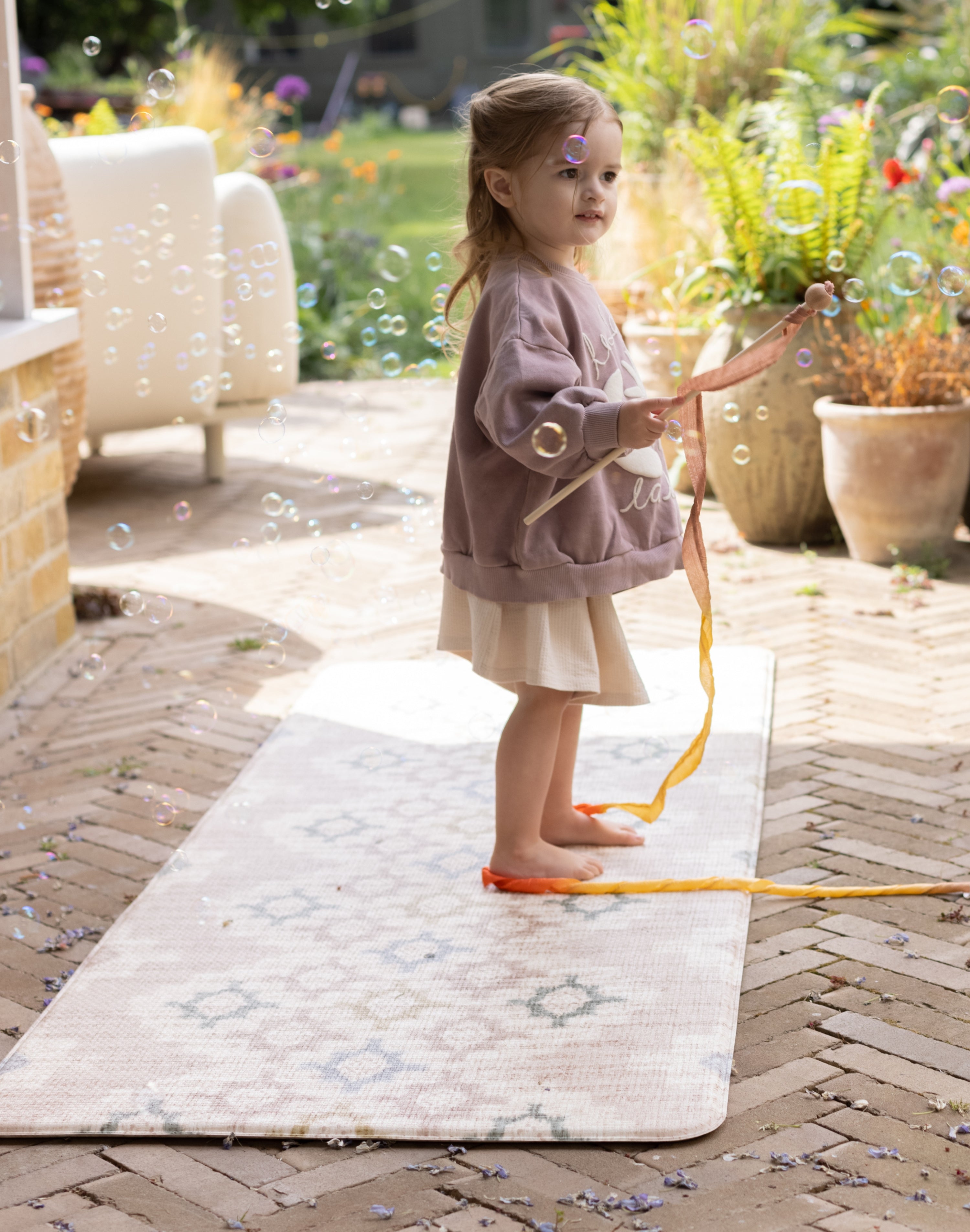 Child playing with a bubble wand on a premium foam outdoor mat 
