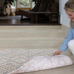 Woman showing both designs of a two-sided play mat for living room 