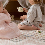 Two children playing with a tea cup on a reversible baby play mat with elegant design
