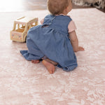 Child playing on a pink flower designer baby play mat safe for crawling 
alfombra infantil premium