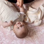 Baby laying on a premium luxury and protective floral pink playmat