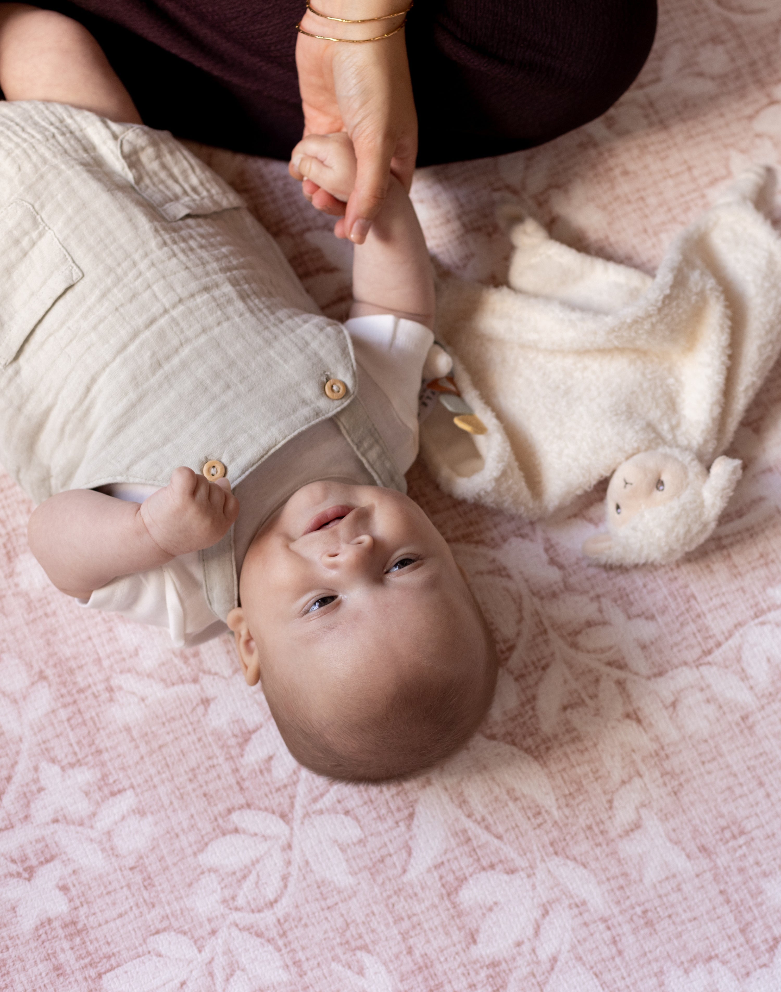 Baby laying on a premium luxury and protective floral pink playmat