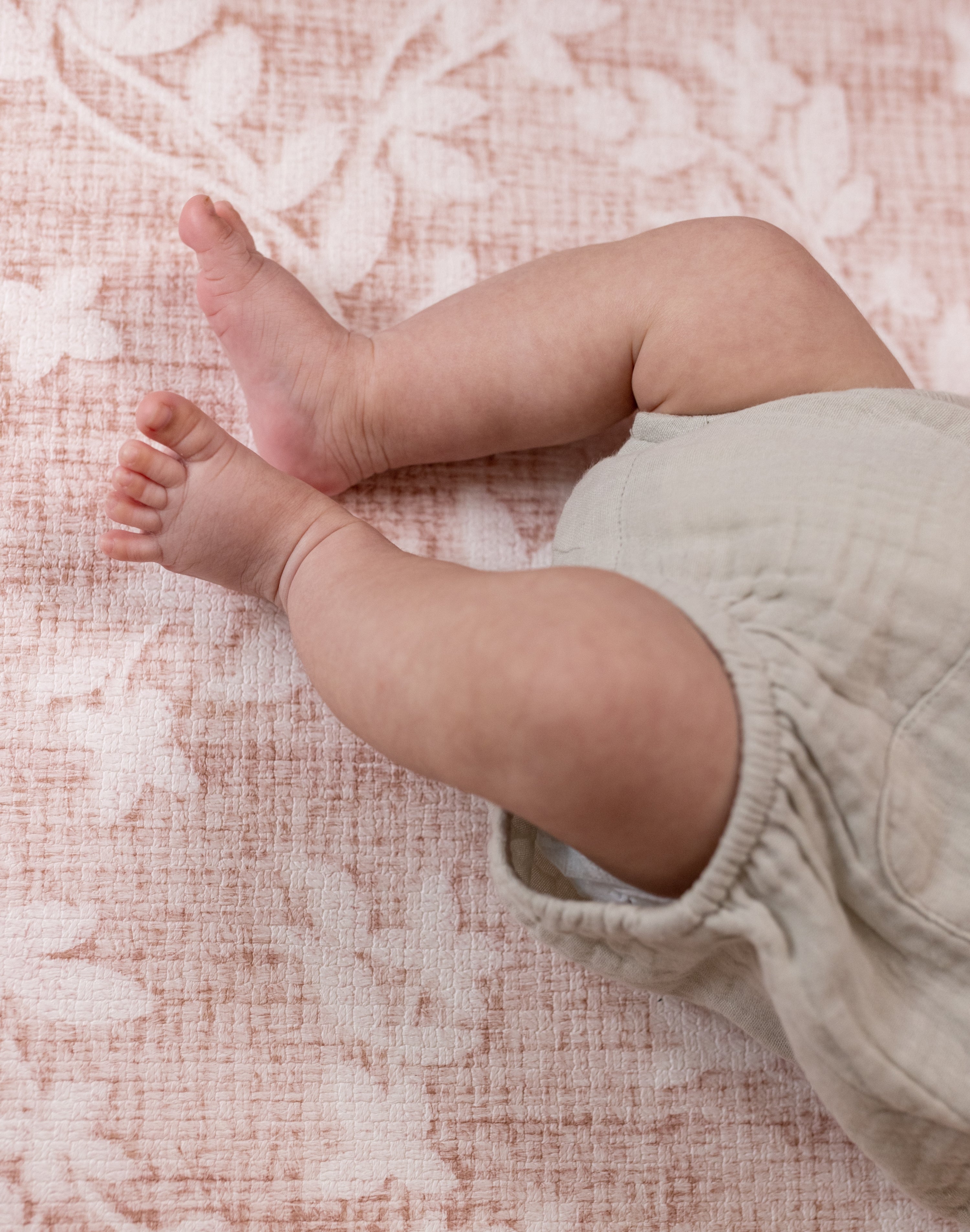 Baby legs on a padded play mat for newborns