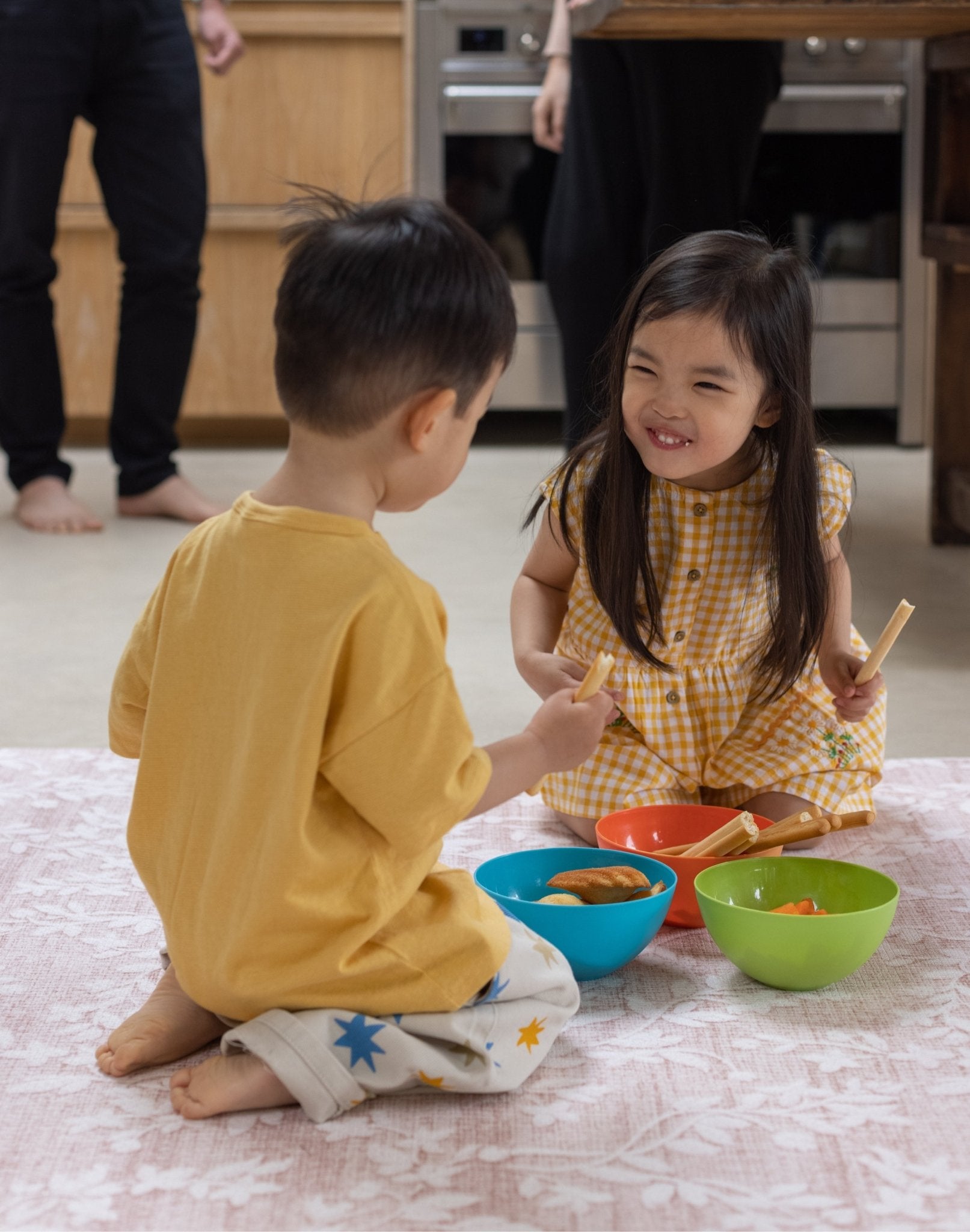 Two children eating food on an easy clean spill proof closed cell wipable rug