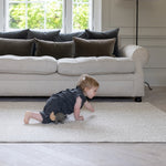 A baby crawls along a Totter + Tumble luxury playmat. It is soft and comfy for crawlers, and first steps.