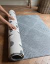 Hands unroll the double sided tapis de jeu for family floor play 