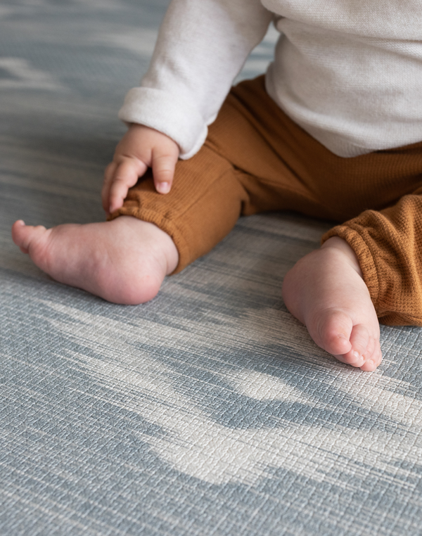 Close up of babies feet and pattern on Blue and beige baby play mat with stylish Ikat design ideal tumbling mat for babies and toddler for safe floor play thick memory foam adds comfort