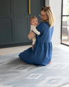 Mother holding baby on Large baby play mat in one piece to unroll in the home squishy memory foam surface to keep floor time comfortable and supported 