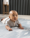 Baby enjoying tummy time on Large round play mat by Totter and Tumble acts like a wipeable rug in the family home easy to clean spit up and spillages and looks stylish
