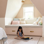 Girl reading on The Brecon, a textured, soft neutral playmat ideal for quiet time and story sessions in kids’ rooms.