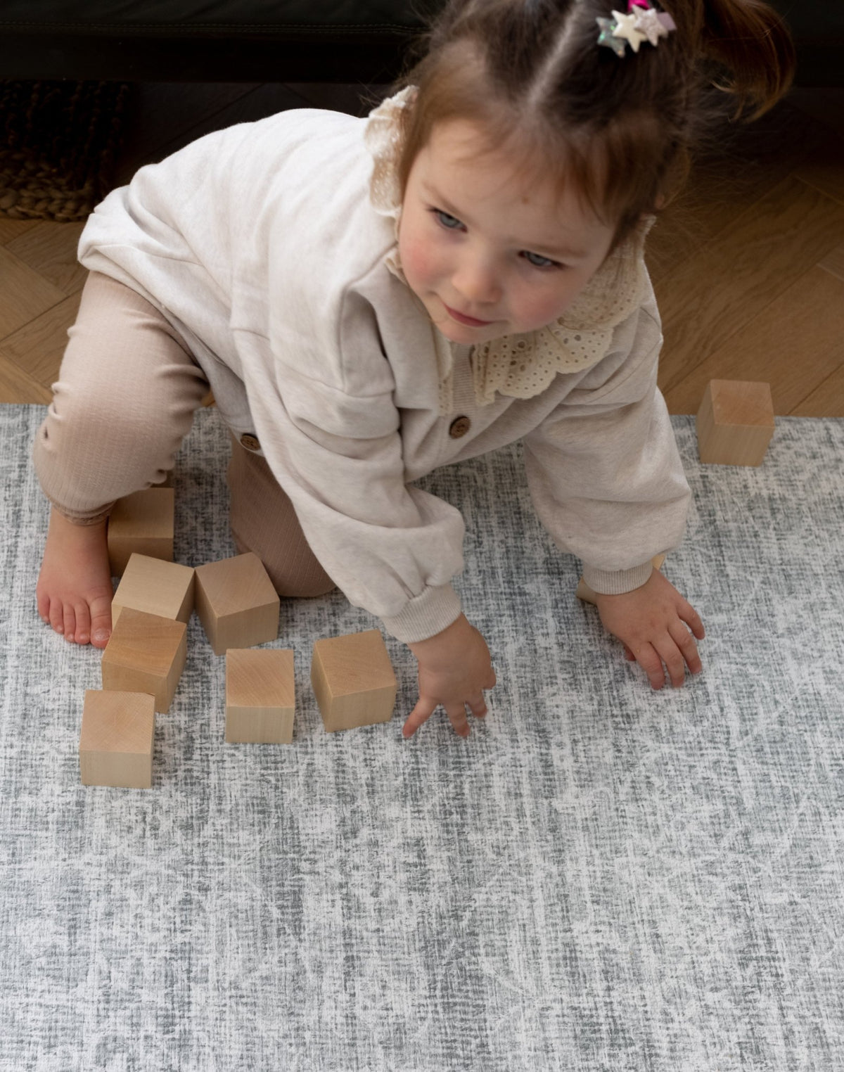 Child playing with wooden blocks on a long lasting reversible baby floor mat