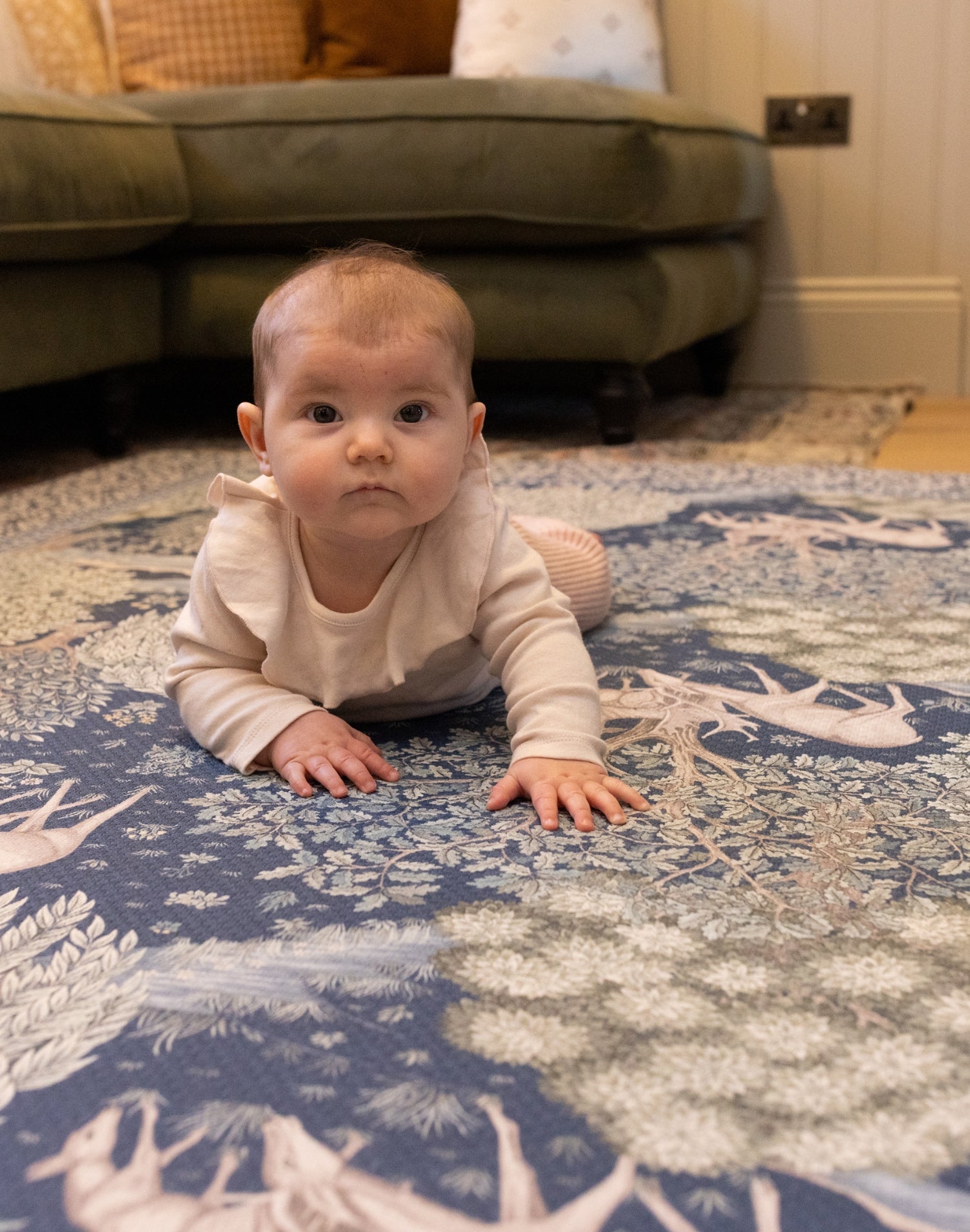 Baby enjoys tummy time on a Totter + Tumble luxury foam play mat in a William Morris botanical design - a non-toxic, stylish baby essential for modern nurseries.