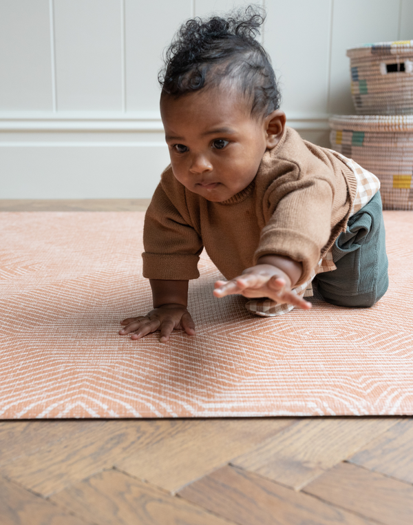 Little boy plays on crawling mat by totter and tumble with a modern orange design 