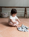 Baby enjoys playing on thick padded floor mat with a sensory black and white muslin 