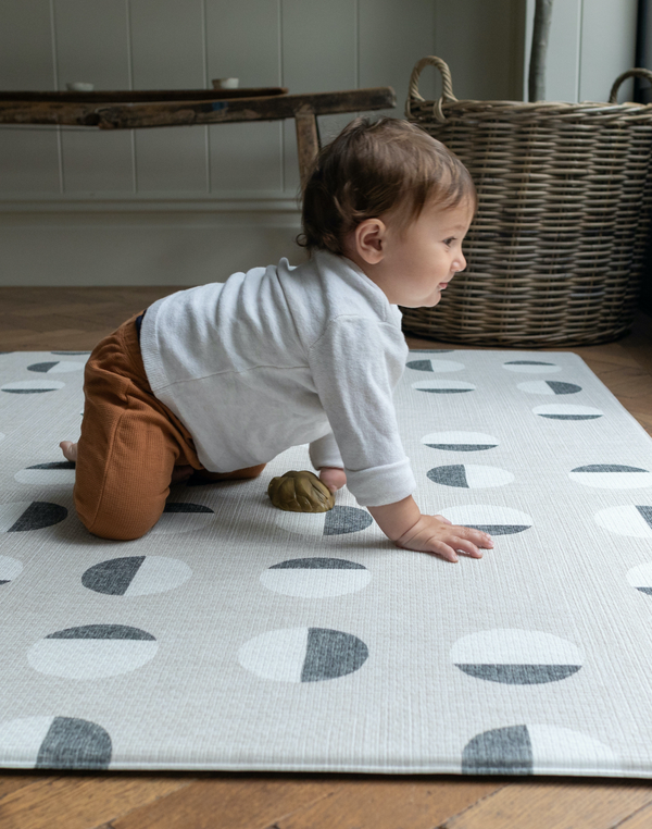 Toddler crawls across a graphic play mat made from luxury memory foam for added support.