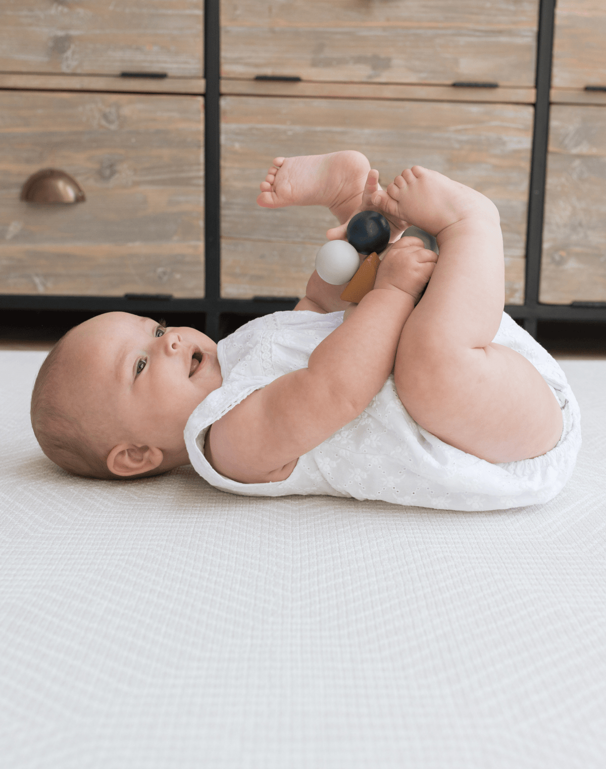 XSmiley baby laying comfortably on thick Kilim play rug designed for babies, adults and stylish family homes 