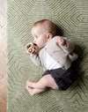 Baby plays on a baby play mat with a thick design to support on the floor during rolling and tummy time 