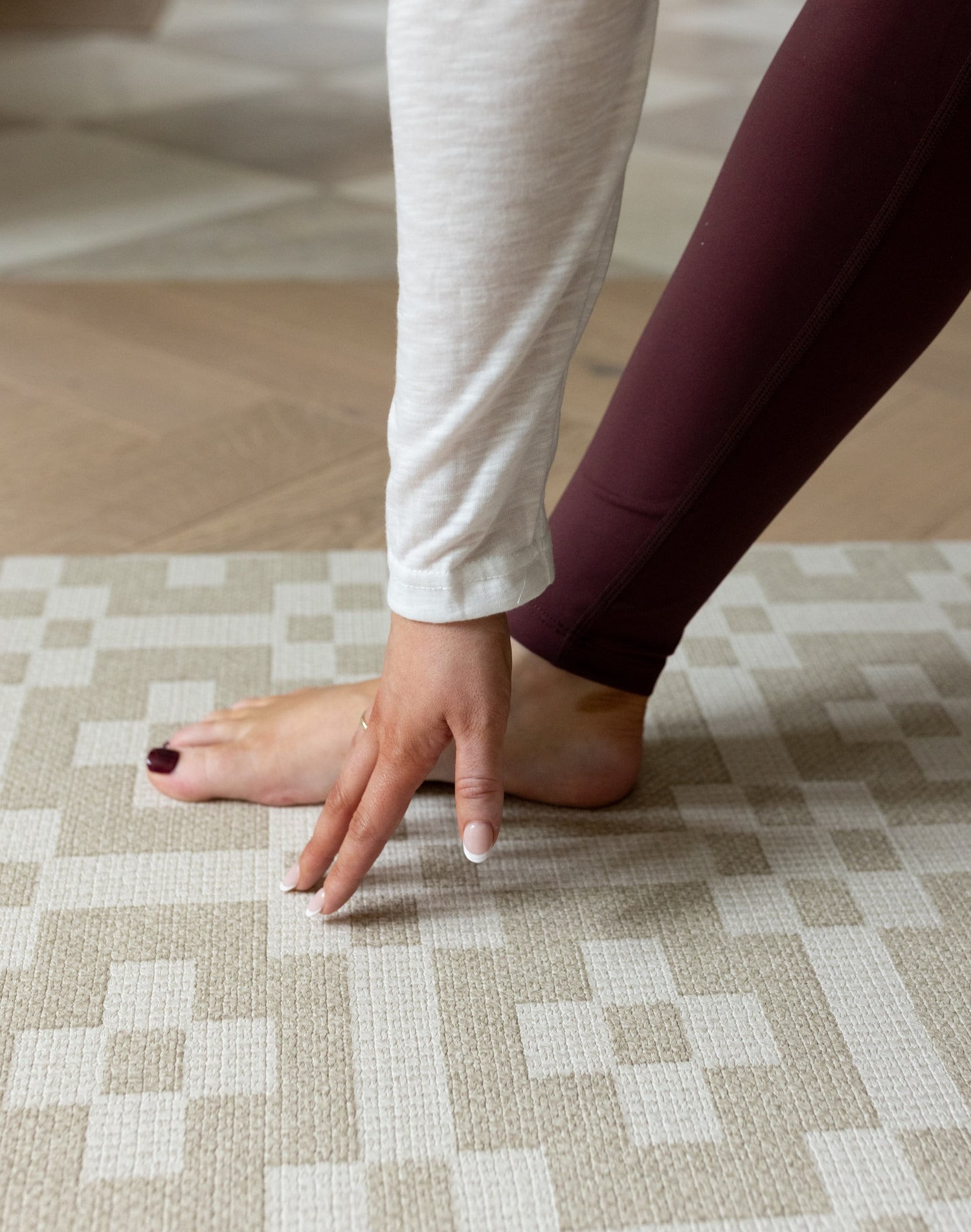 A lady does yoga on The Holbein, a textured baby playmat with a handwoven style and earthy calming tones.