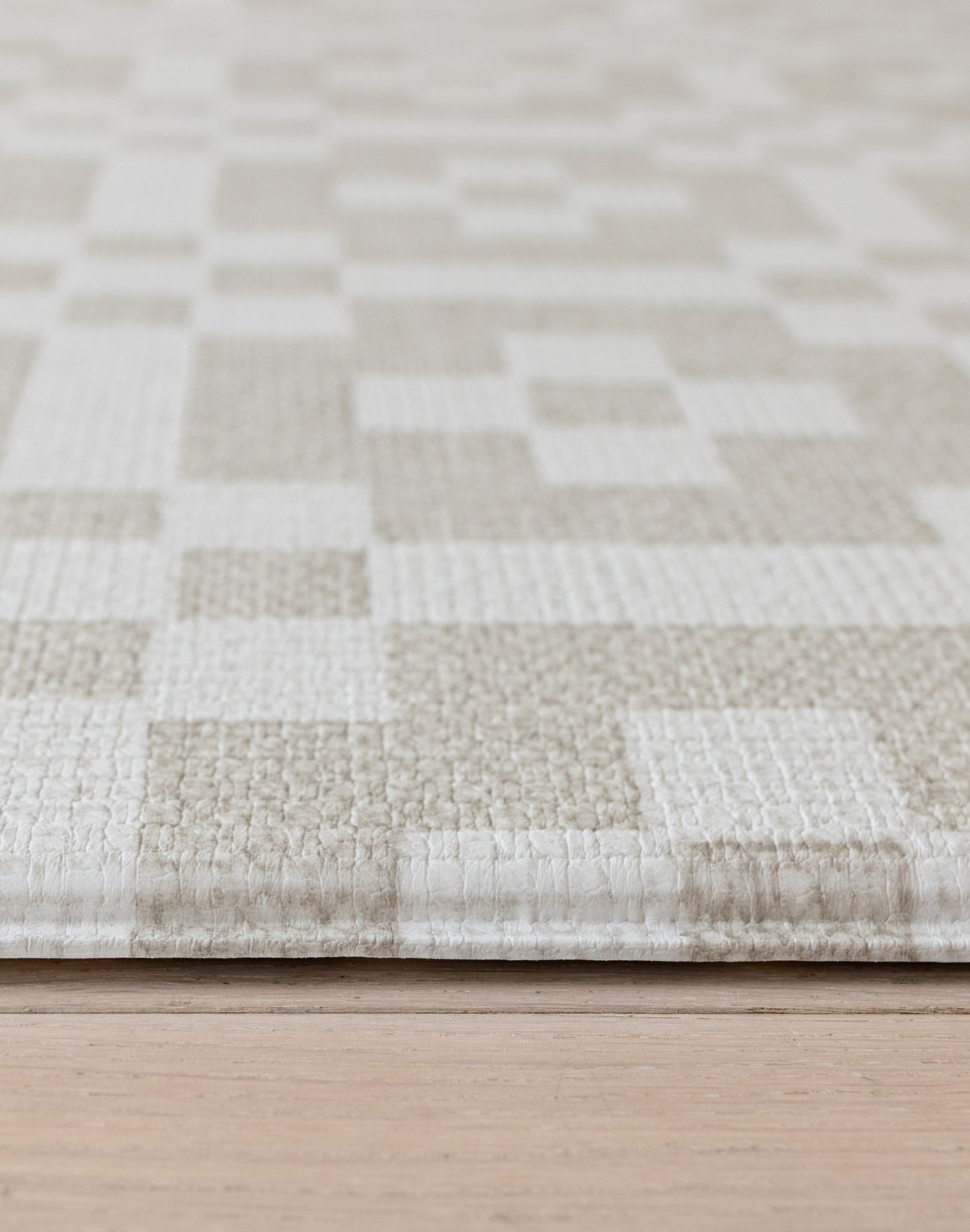 Corner close-up of The Holbein, a Welsh tapestry playmat with textured, tufted surface in natural tones.