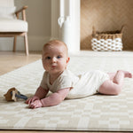 Baby on The Holbein, a calming colour play mat with a Portcullis motif in stone and chalk for tummy time and play.