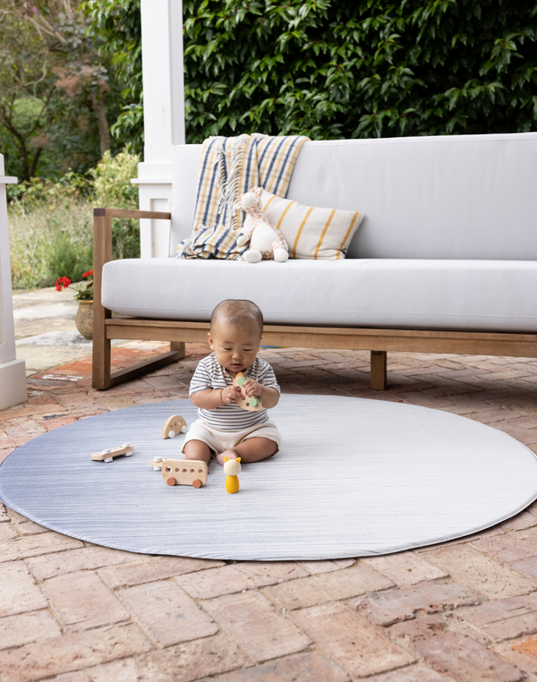 Baby playing on padded round play mat on the patio enjoying floor play in comfort keeping body cool on hot tiles 