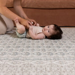 Baby lying on soft grey Totter & Tumble large playmat in stylish living room