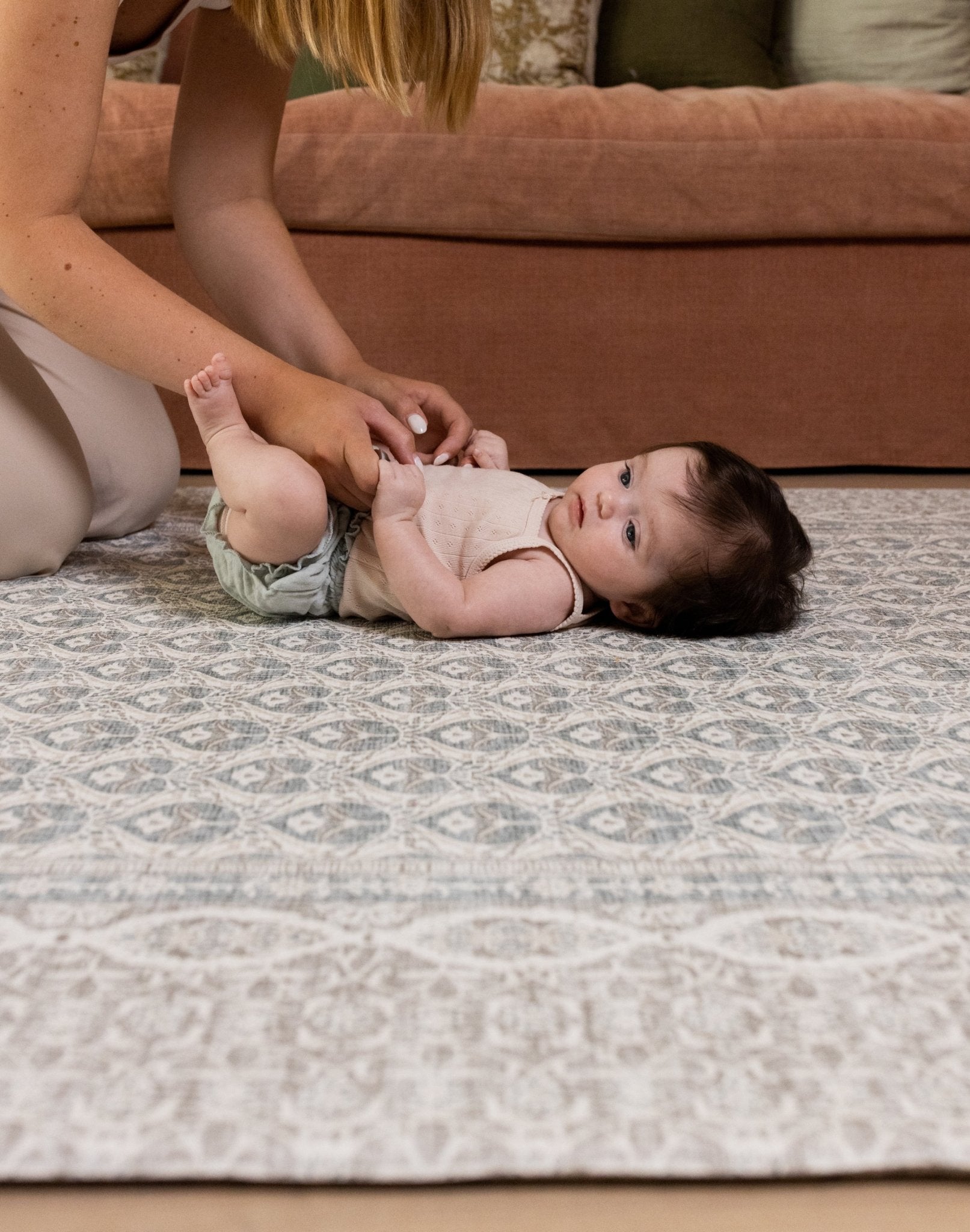 Baby lying on soft grey Totter & Tumble large playmat in stylish living room