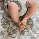 Baby's feet  lying on a soft grey textured playmat