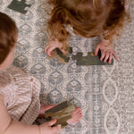Two toddlers playing with toys on washable large baby mat in soft colours