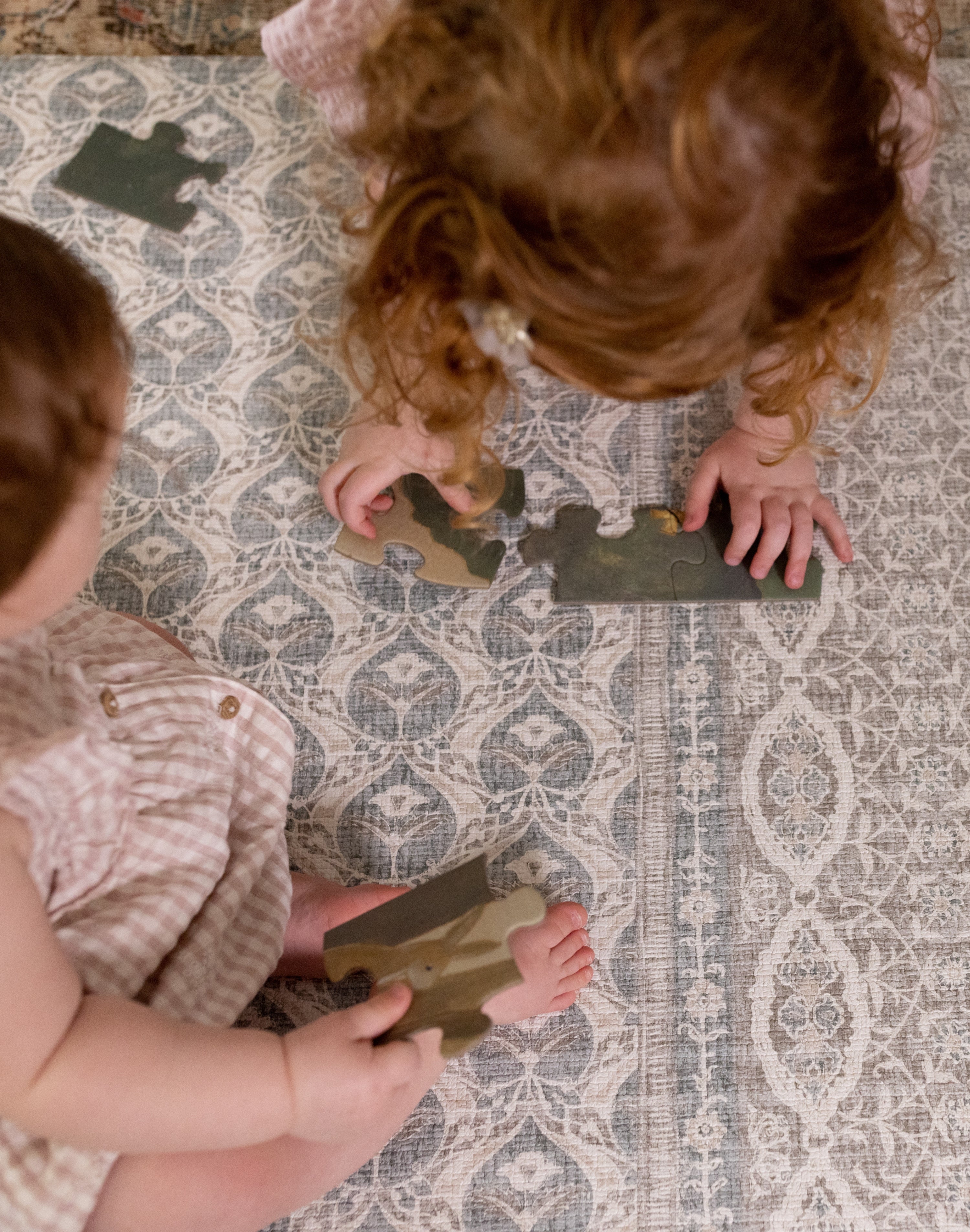 Two toddlers playing with toys on washable large baby mat in soft colours