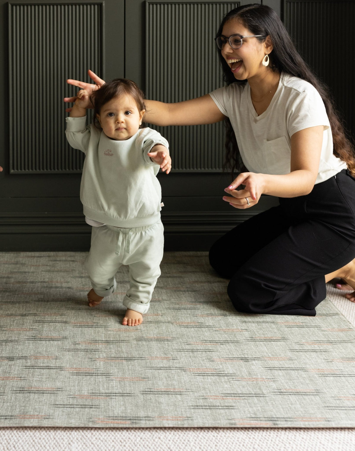 Woman and child learning to walk on a impact absorbing baby mat