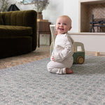 Happy baby playing on a large playmat in a stylish interior setting