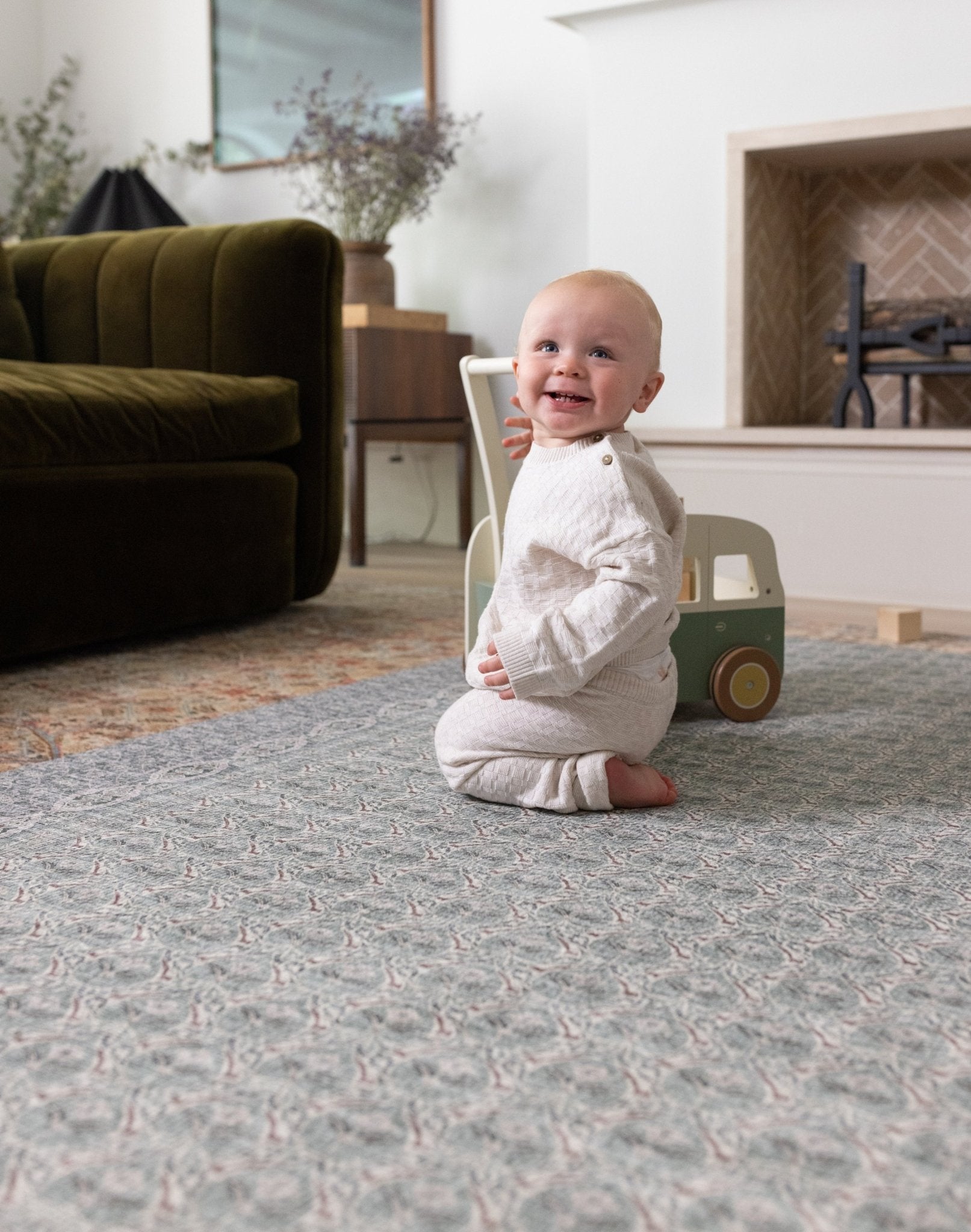 Happy baby playing on a large playmat in a stylish interior setting