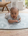 Round play mat for hard floors by Totter and Tumble so little ones don't feel the floor underneath with stylish green and beige ikat design for a stylish look 