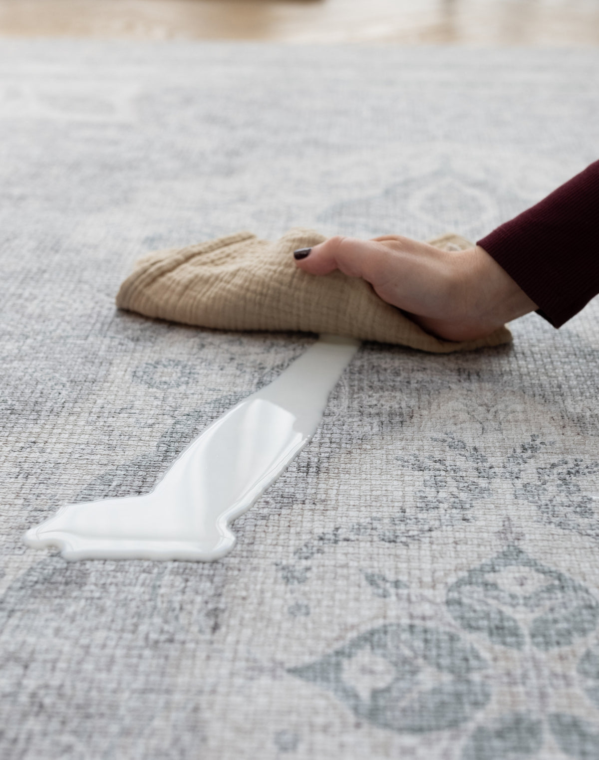 A hand cleans up a milk spillage with a soft cloth on large waterproof play mat | SKU: 24 PORTO/BRIM XL