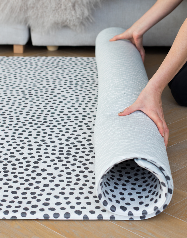 Hands unroll an ultra-thick memory foam baby play mat designed for extra comfort and support