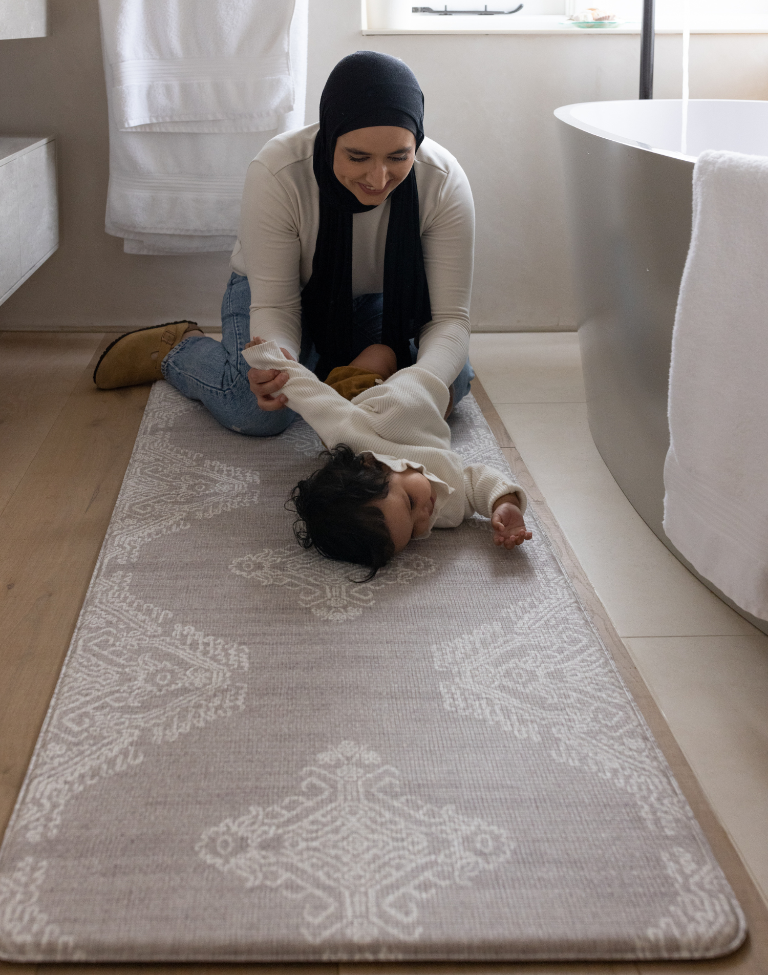 Mum changes baby on the extra large bathroom mat with a thick memory foam design for comfort during changing and a waterproof surface so water drops can be cleaned up with ease