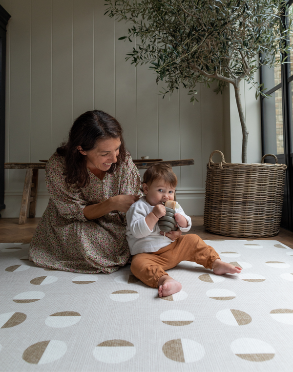 Lady and child sit together on tan one piece play mat with a modern design that looks great in modern living space 
