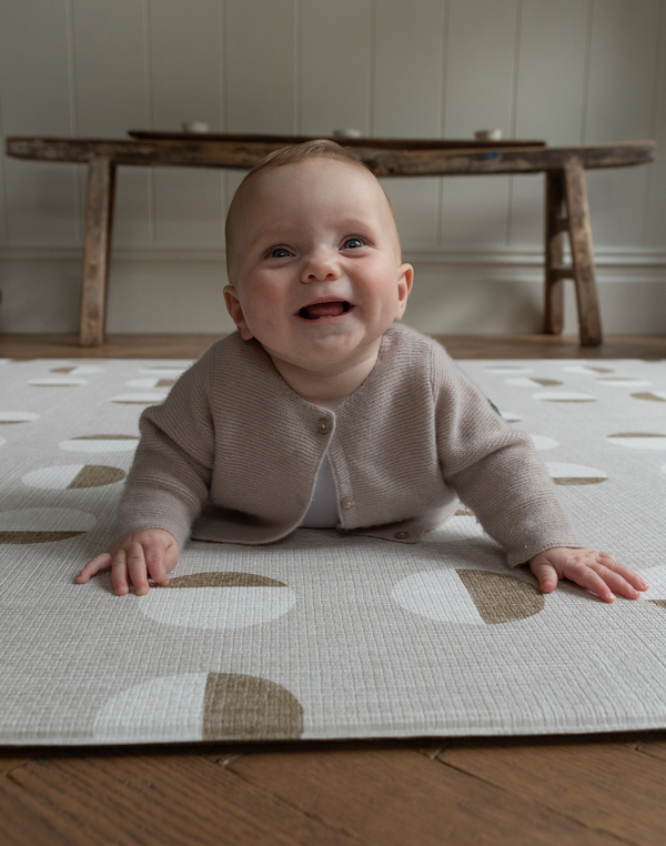 Happy baby enjoys tummy time on baby play mat with durable supportive design 