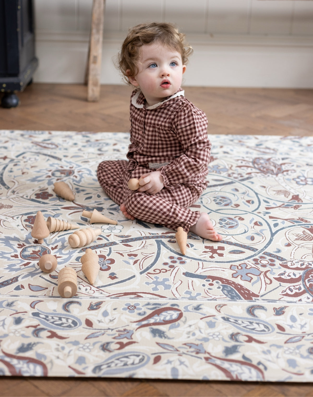 Child playing with wooden toys on a protective elegant baby crawling mat.
