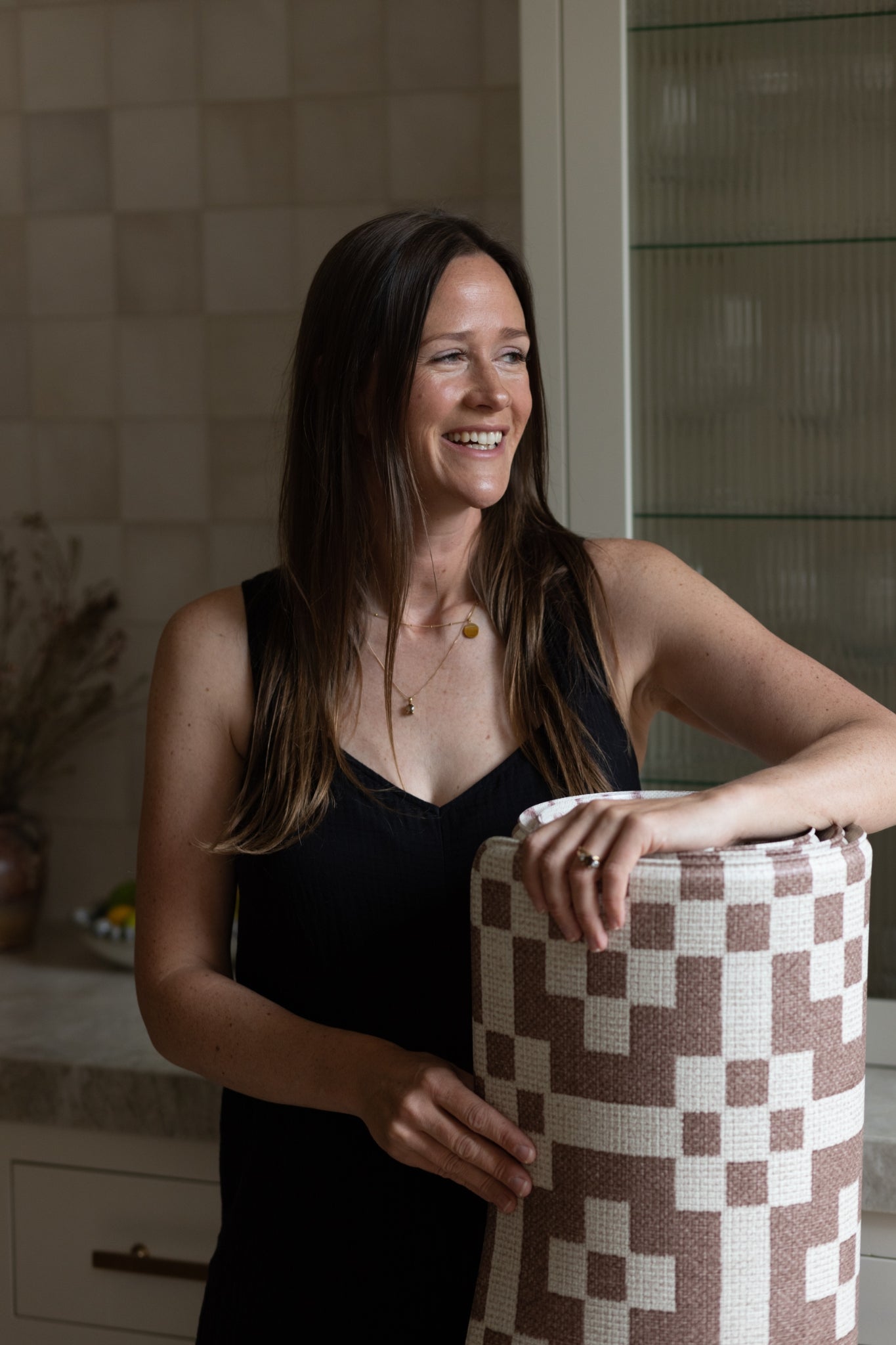Susie Stubbs- Founder at Totter + Tumble holds a rug-like textured baby playmat.