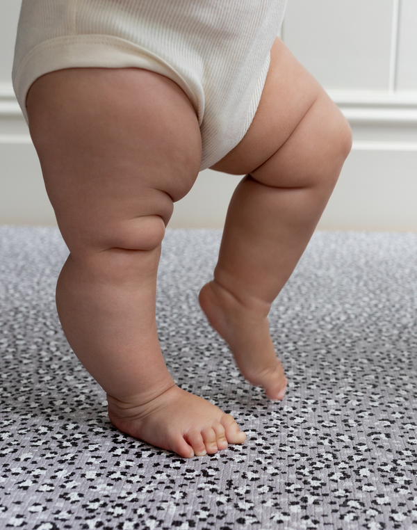 Baby practices standing on foam mat with textured surface for added support 