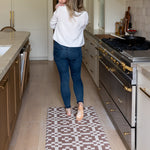 Woman holding a baby in a modern kitchen with a roasted umber playmat on the floor in a runner style