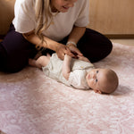 Woman playing with a baby on a safe cushioned play mat for crawling