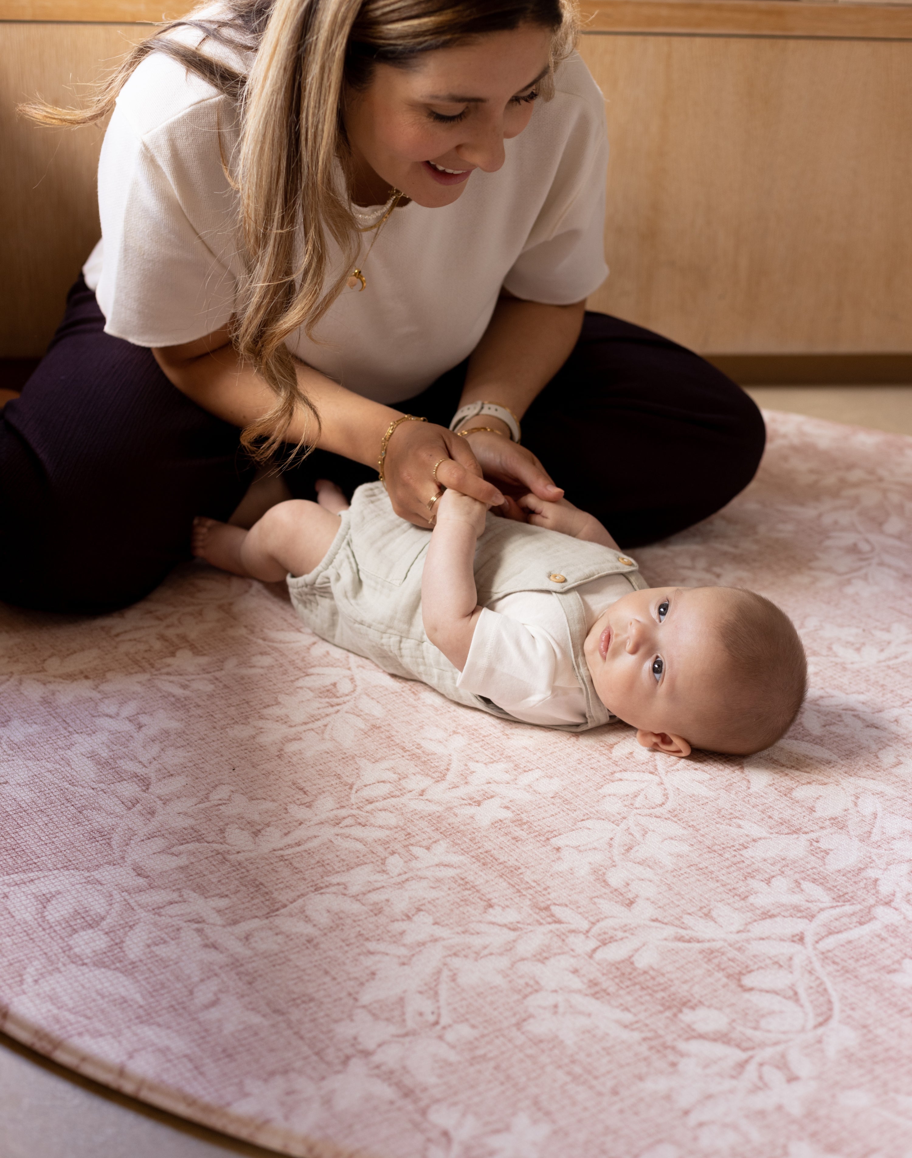 Woman playing with a baby on a safe cushioned play mat for crawling