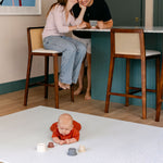 A baby enjoying tummy time in the kitchen on the beachcomber totter and tumble playmat | SKU: 26 BEACH/GATHER XL, 26 BEACH/GATHER STD, 26 BEACH/GATHER COMP