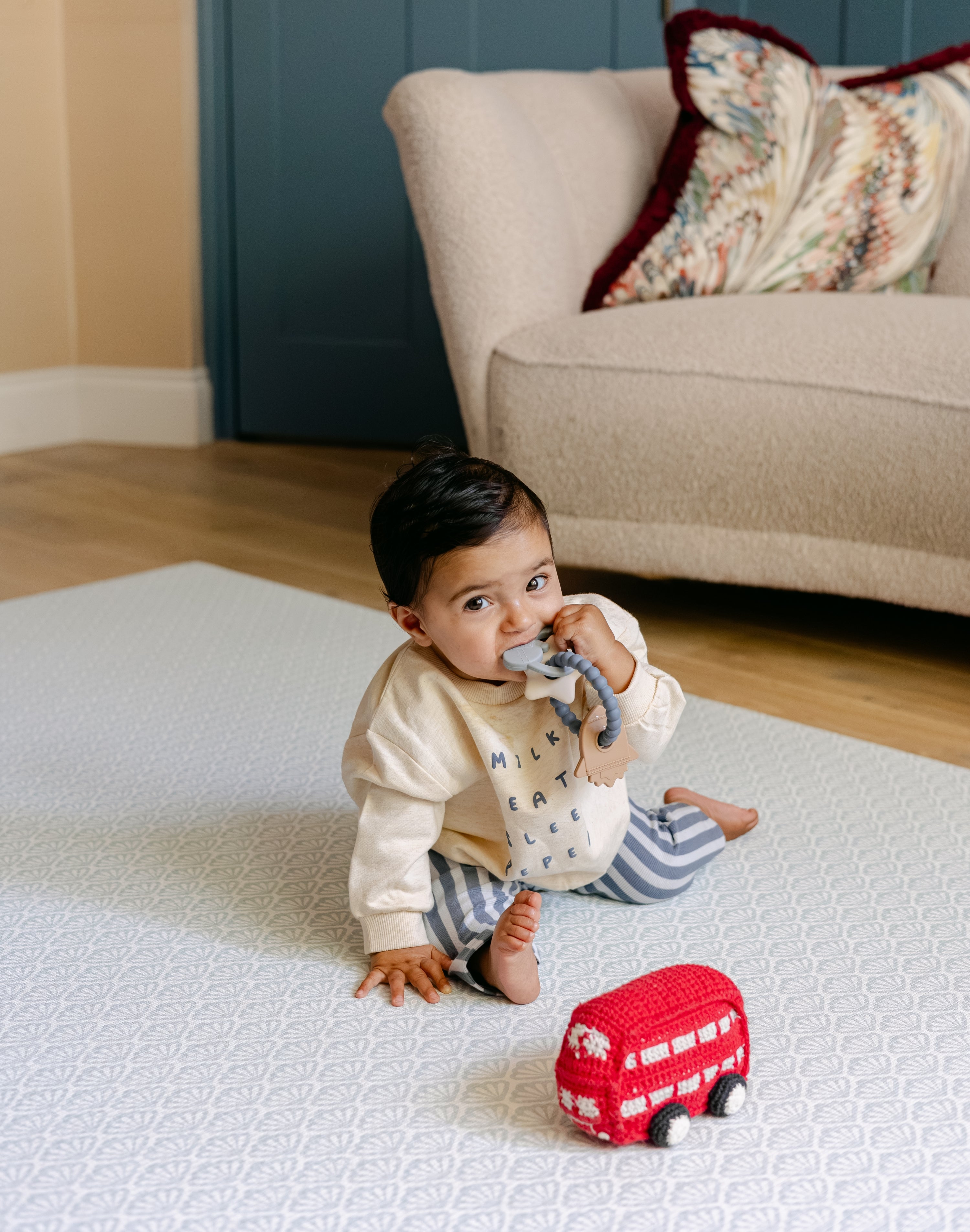 A baby playing comfortably on the rug-like shell design beachcomber blue playmat from totter and tumble | SKU: 26 BEACH/GATHER XL, 26 BEACH/GATHER STD, 26 BEACH/GATHER COMP